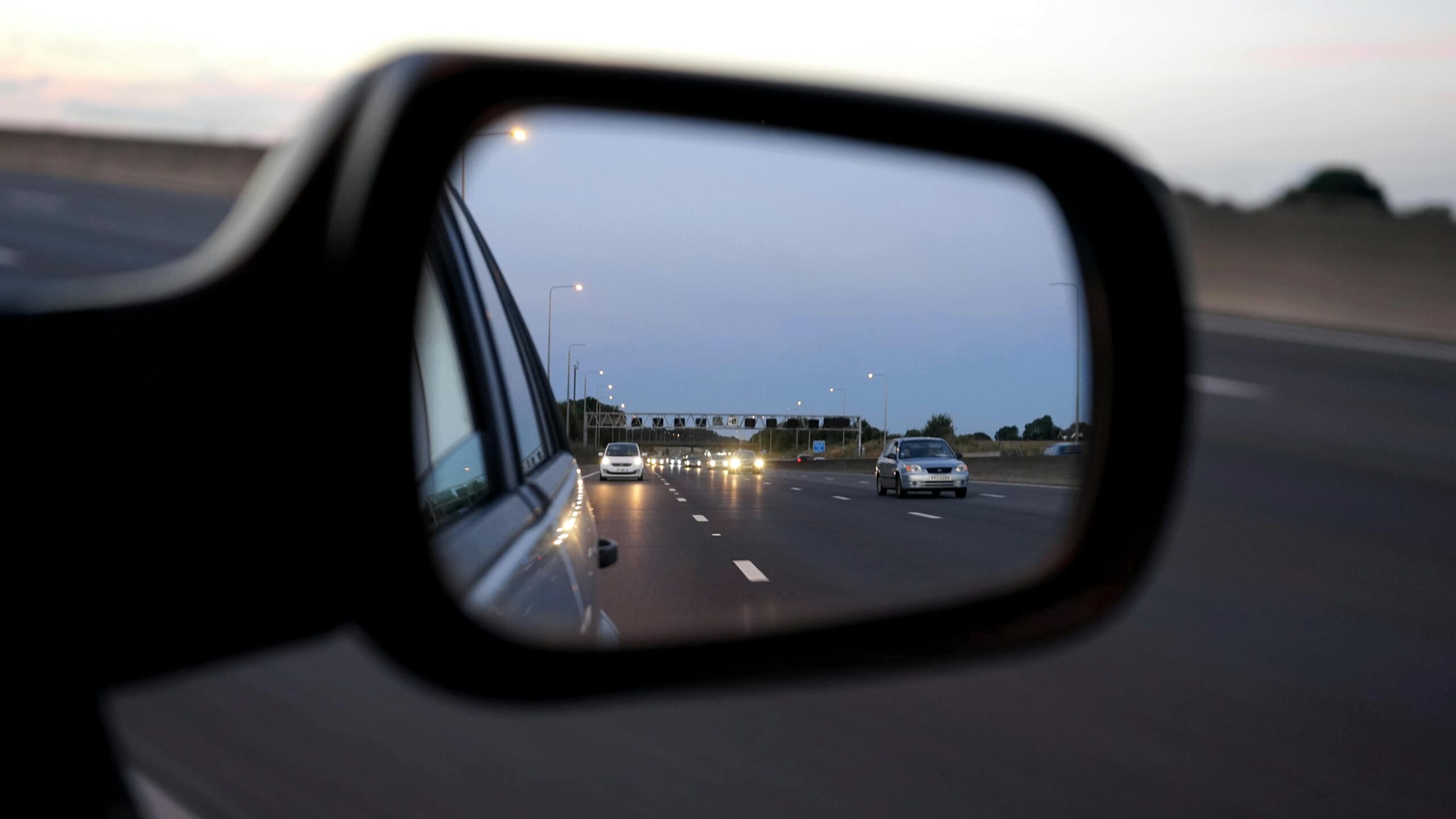 Image of side mirror of a car with the reflection of a road.